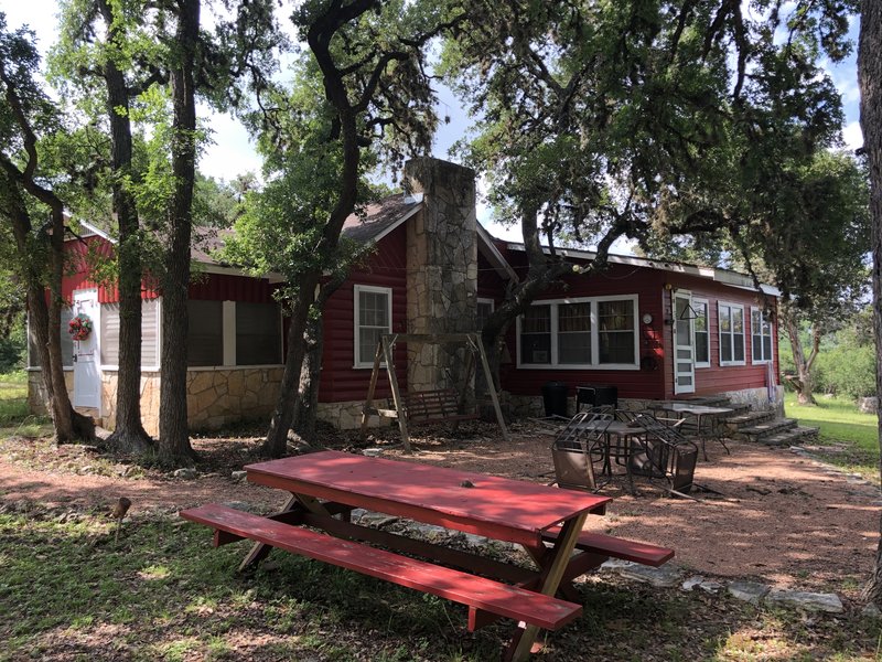 Bandera River House — red cabin under oaks